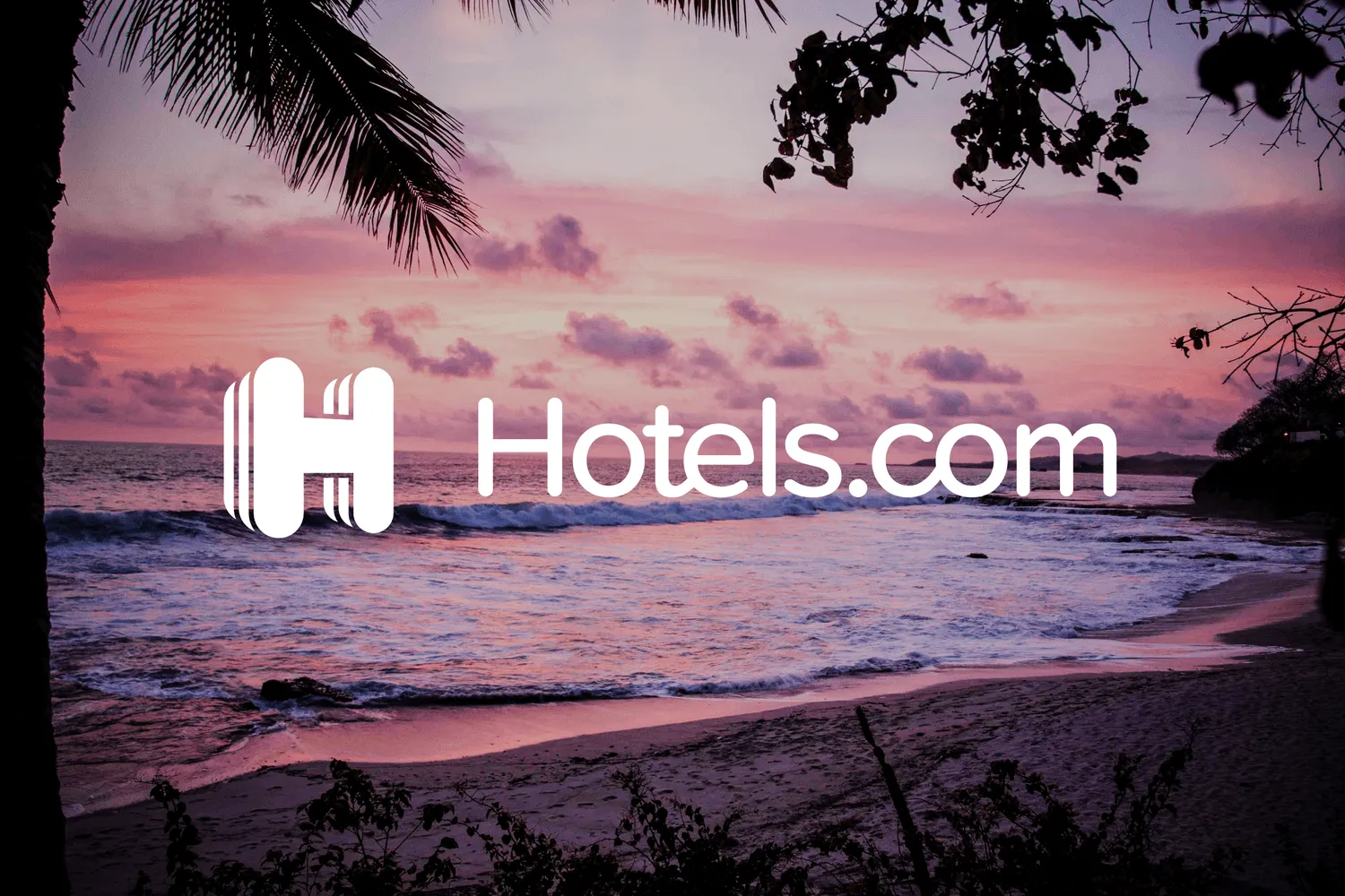 The white Hotels.com wordmark and striped H over a pink sunset beach, framed by palm fronds.